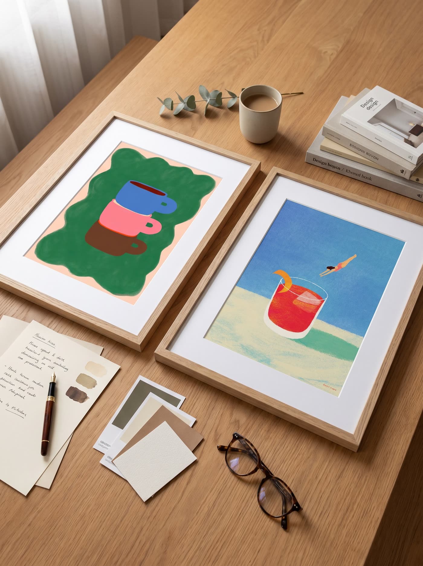 Framed art posters on an oak table with paper samples